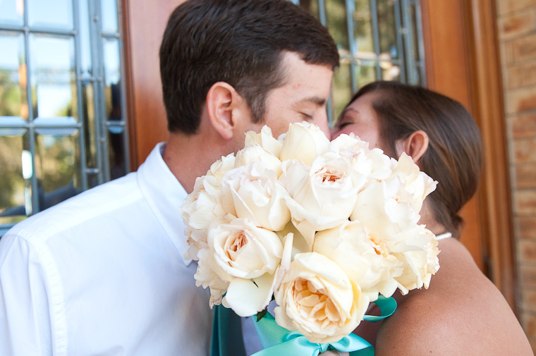 Joni and Matt kiss with bouquet partially blocking their faces